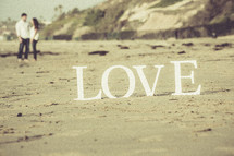 a couple standing on a beach and the word LOVE