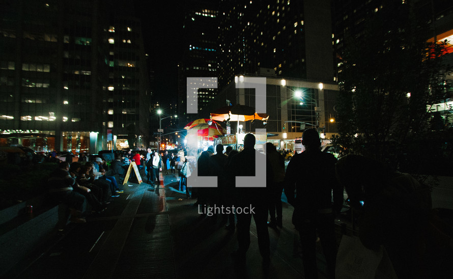 people gathered at a city street market at night 