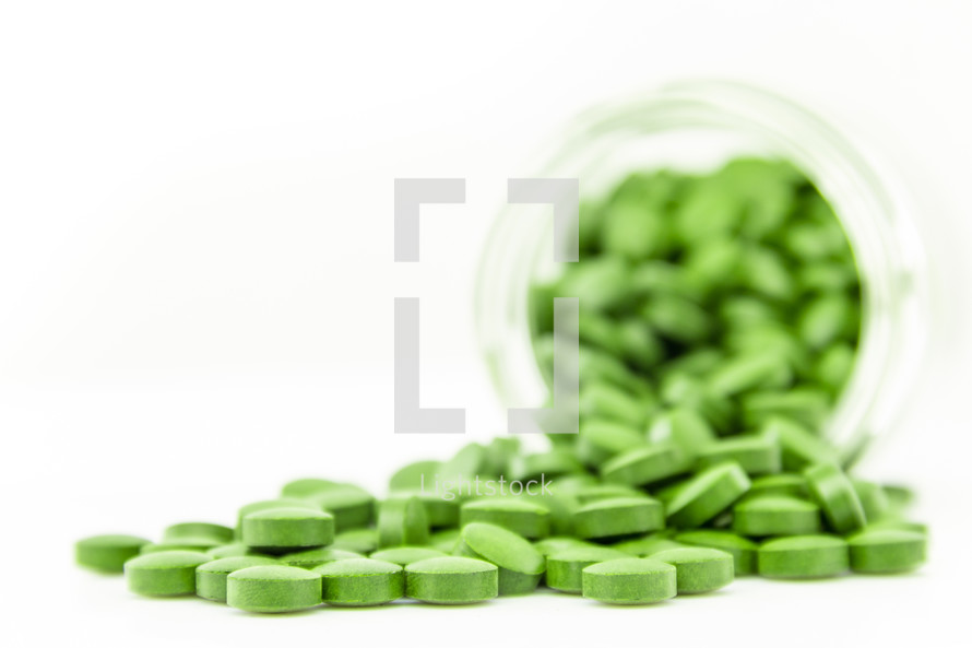 A bottle of spilled green pills.