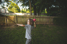 A boy child throwing a football in the backyard. 