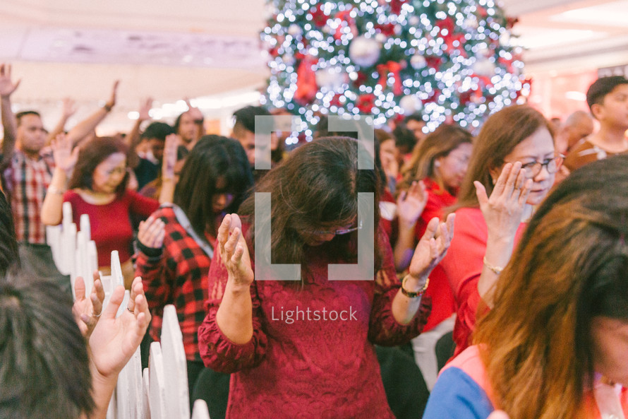 raised hands in prayer at a Christmas worship service 
