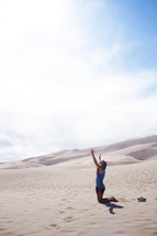 a woman kneeling in sand 