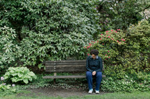 a woman sitting on a park bench praying 