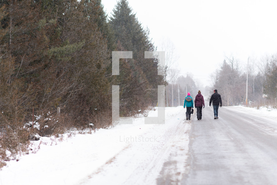 people walking down a snow covered road 