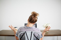 a woman with her hands up sitting in front of a computer desk 