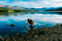 a man looking under rocks in a pond 