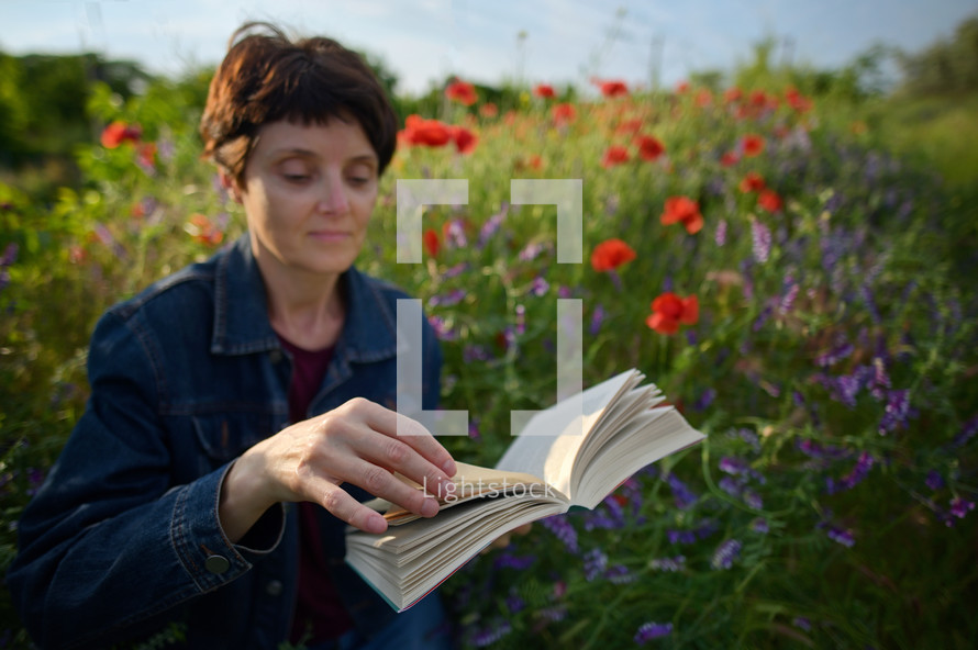 a woman reading a book in a field of wildflowers 