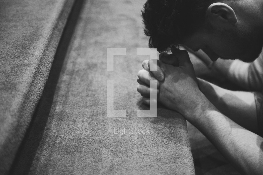A man kneeling in prayer at the altar 