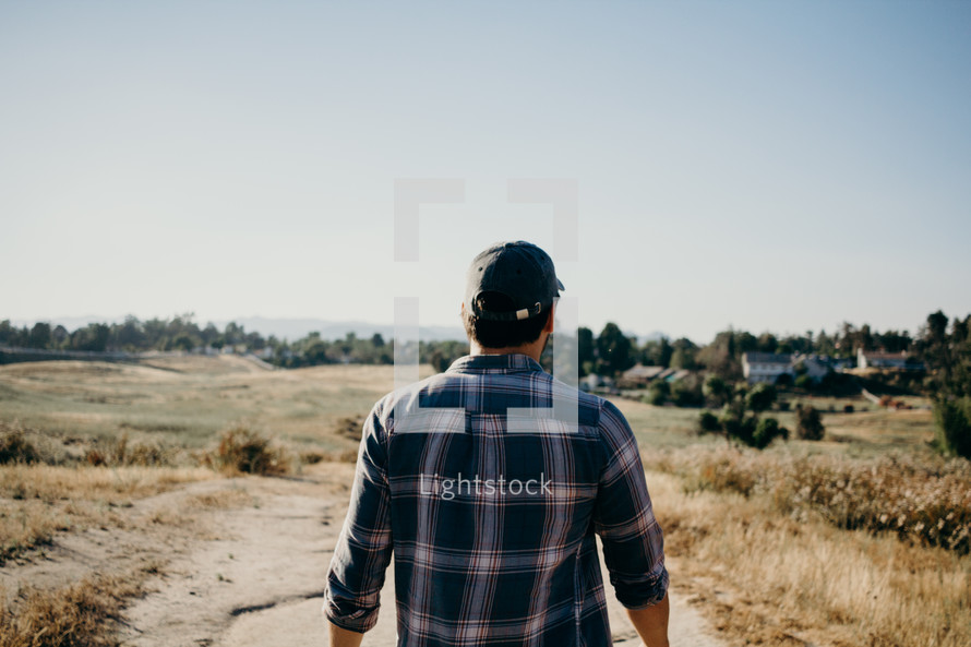 a man in a plaid shirt walking outdoors 