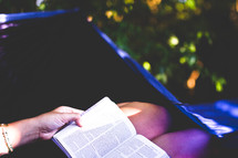 woman reading a Bible on her lap outdoors 