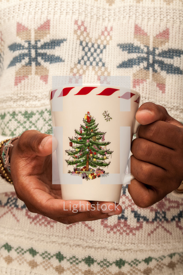 a man in a Christmas sweater holding a mug 