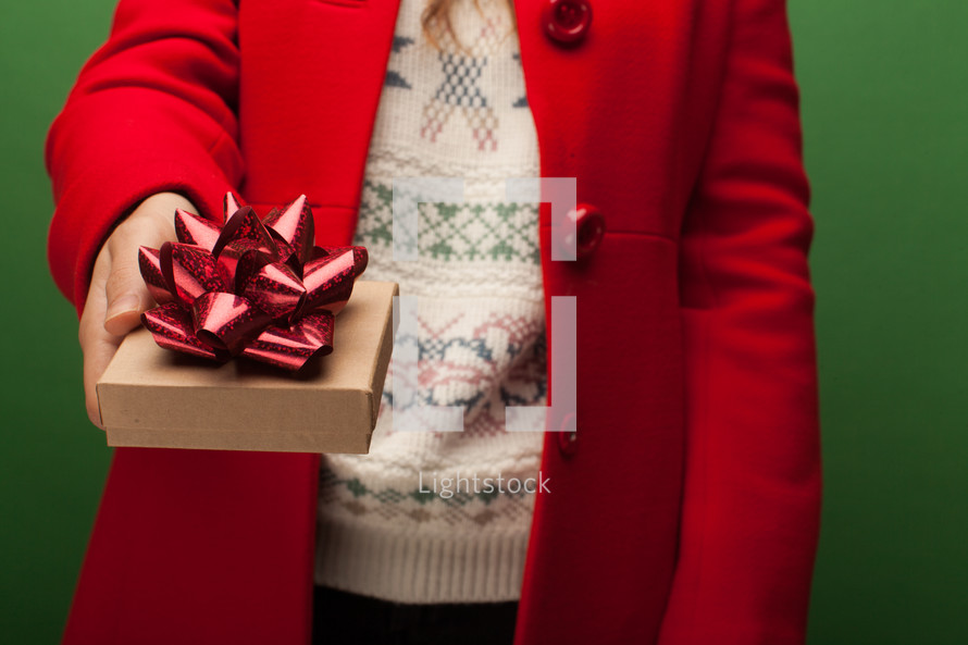 a woman in a red coat giving a gift at Christmas 