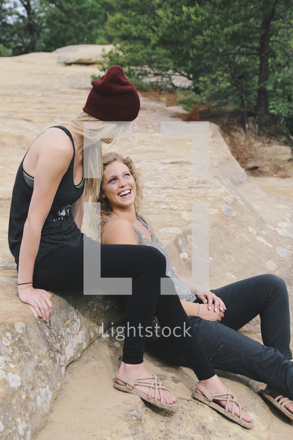 women sitting on rocks talking 