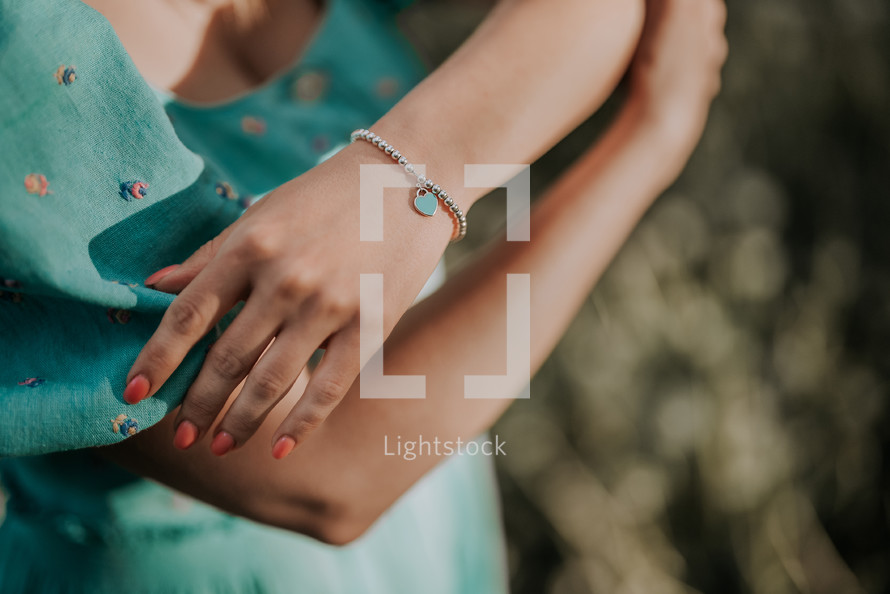 Female Hand With Silver Beads Bracelet And Blue Heart Charm. Turquoise Jewelry