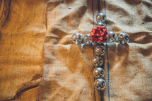 cross of silver Christmas ornaments on burlap 
