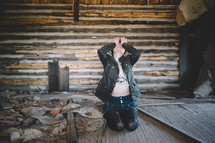 A woman sits with head in hands in an abandoned log house.