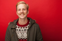 man with a mustache in a Christmas sweater and coat 