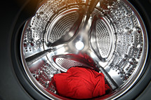 View of the tumble dryer or washing machine drum with red clothes inside. Laundry day. Daily household chores. Domestic and Household Appliance. Home Innovation