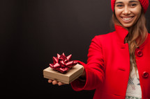a woman in a red peacoat holding a gift box for Christmas 