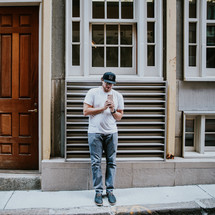 man standing on a street corner texting 