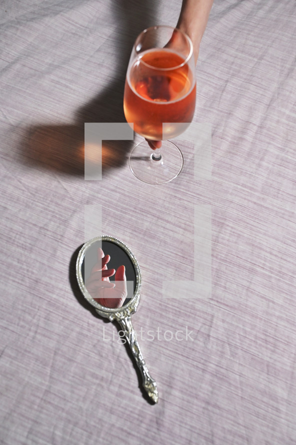 Abstract Hand in Vintage Mirror and Woman hand holding Glass of Rose Wine
