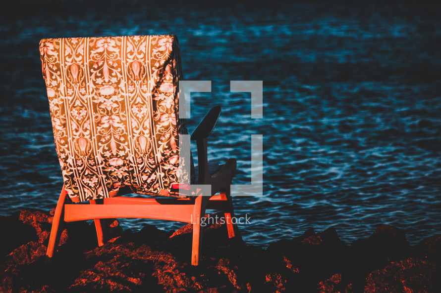 chair on rocks along a shore 
