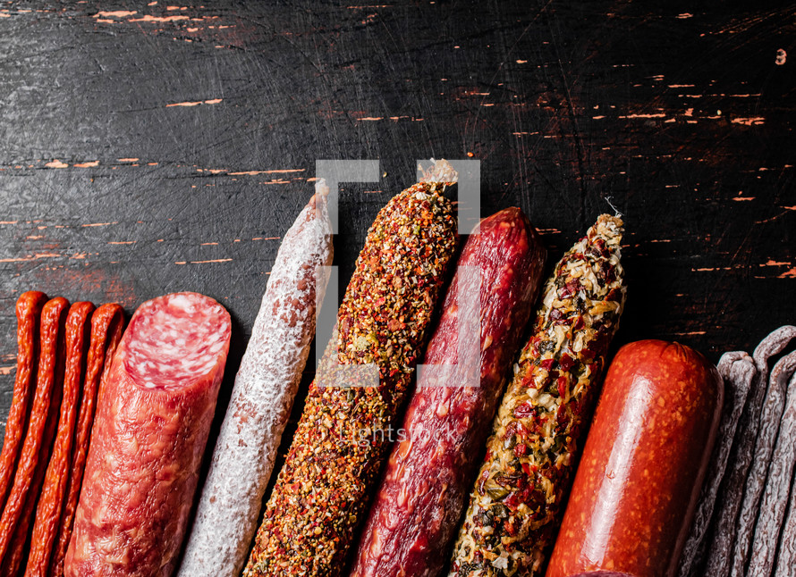 Assortment of various aromatic salami sausages. Against a dark background. High quality photo