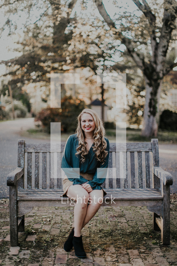 a young woman sitting on a wooden bench 