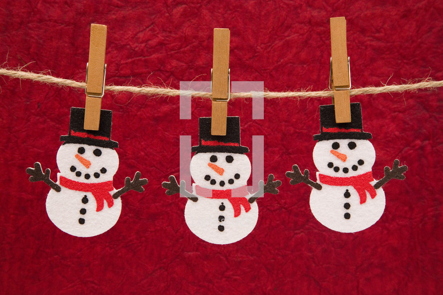 snowman cutouts hanging on a clothespins 