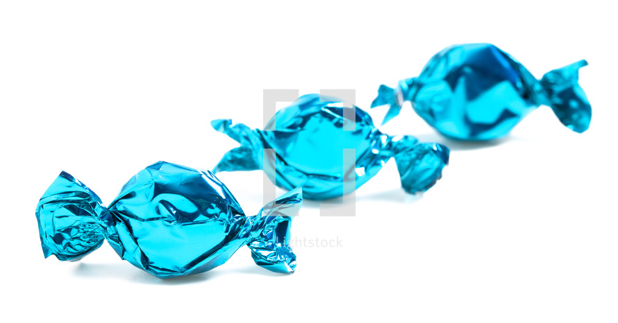 three blue wrapped candies on a white background 