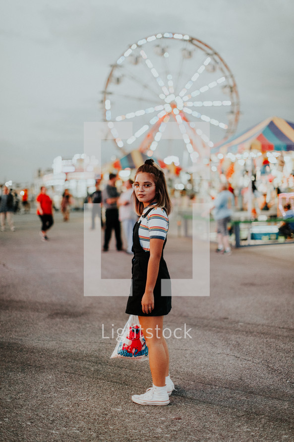 teen girl holding cotton candy at a fair 
