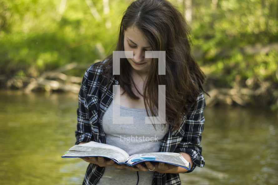 woman reading a Bible standing in water 