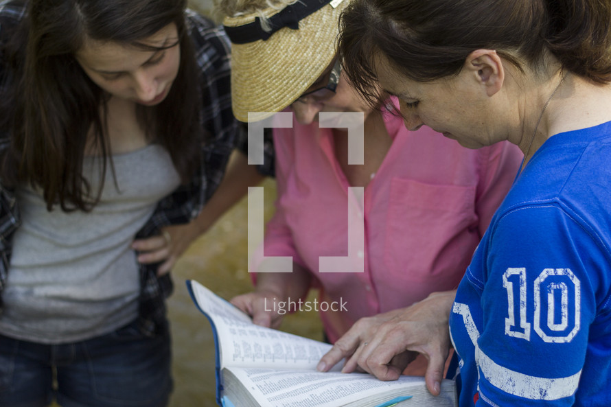 Three women looking at a passage in the Bible.