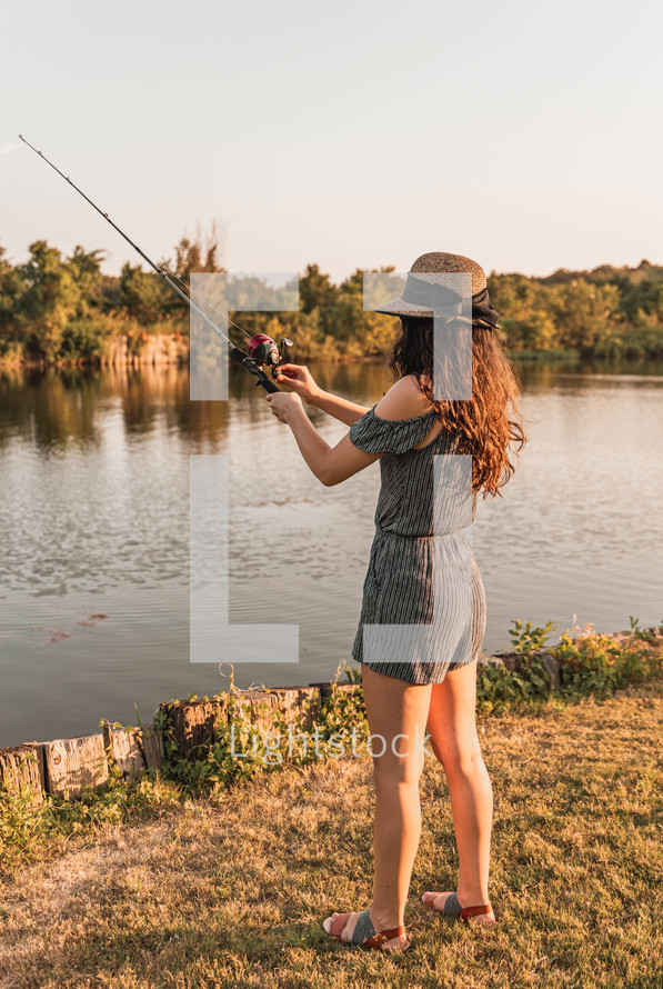 young woman fishing on a lake shore 