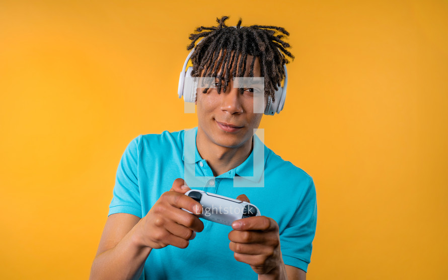 Handsome young man playing video exciting game on Tv with joystick isolated on yellow studio background. Using modern technology. High quality photo
