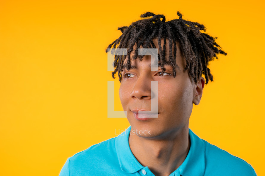 Friendly african american young man with dreadloocks on yellow studio background. Copy space. Teenager student guy. High quality photo