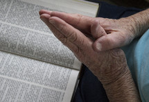 praying hands over a Bible