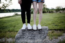 legs of a couple standing on a rock 