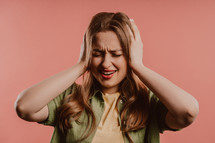 Woman afraid of something, she in shock on pink backdrop. Holding head, screaming. High quality photo