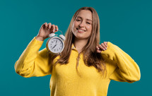 Happy lady with alarm clock on teal background. Early morning, correct day routine, living in moment, appreciate every minute of life, youth. High quality. High quality photo