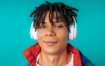 Positive young african american man listening music, enjoying dance with headphones on blue studio background. Radio, wireless modern sound technology, online player. High quality. 