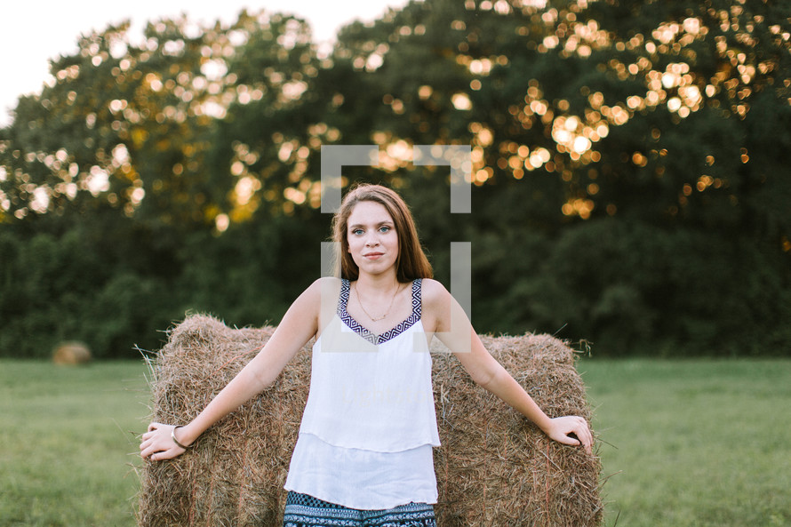 teen girl leaning against a hay bale 