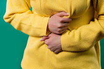 Woman squeezing belly with hands because of abdominal pain. Lady suffering from stomach ache. Healthcare, problem with menstrual period cramps or bowel flatulence concept