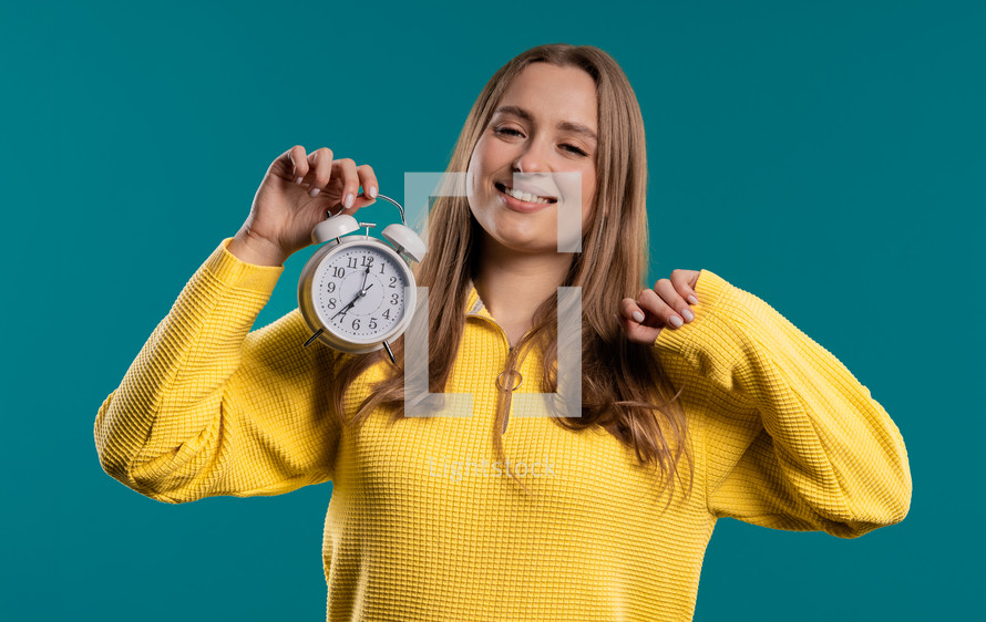 Happy lady with alarm clock on teal background. Early morning, correct day routine, living in moment, appreciate every minute of life, youth. High quality. High quality photo