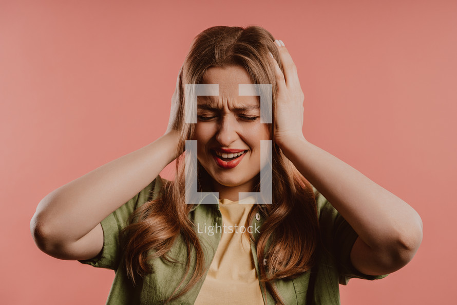 Woman afraid of something, she in shock on pink backdrop. Holding head, screaming. High quality photo