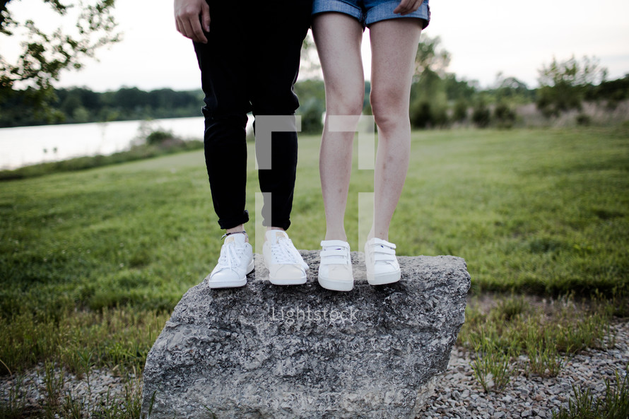 legs of a couple standing on a rock 
