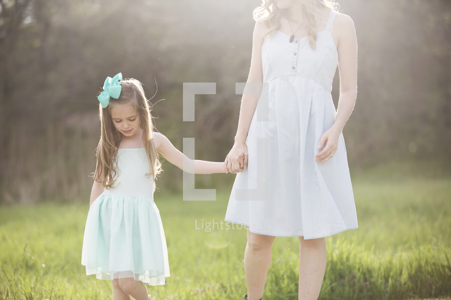 a mother and daughter holding hands outdoors 