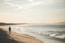 a man walking on a beach at sunrise 