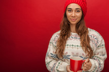 a woman in a wool cap holding a mug 