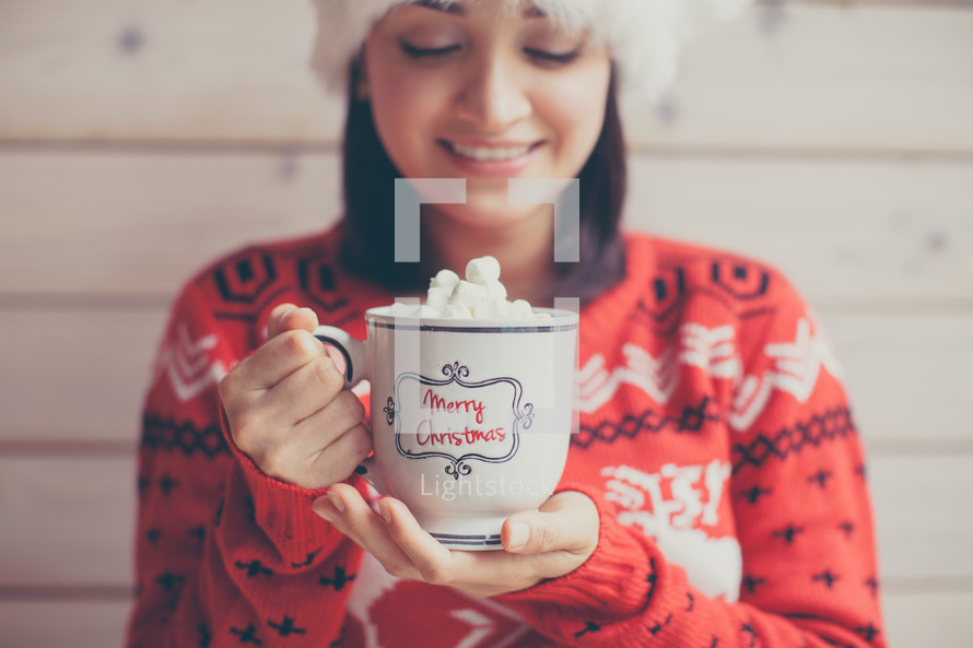 a woman in a Santa hat holding mug of hot cocoa 